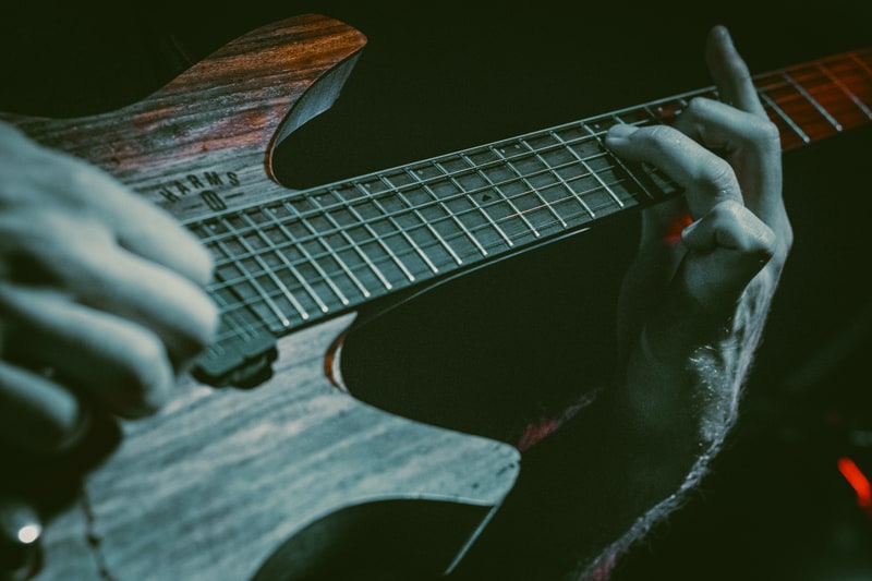 Close view of Saul's fretting hand, strings and the natural grain of his guitar.